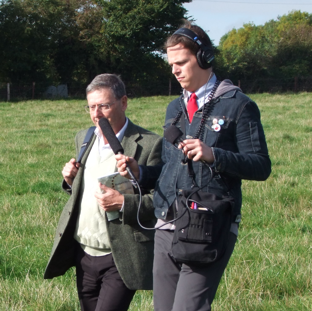 Sam sitting at a table working on a laptop with over the ear headphone on